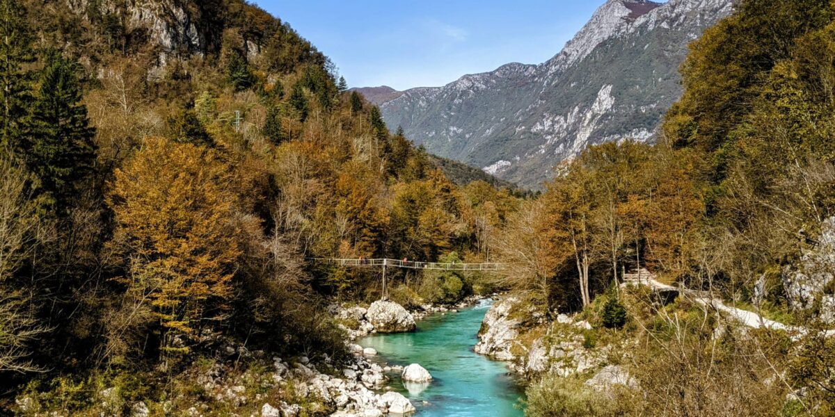 Autumn colours in Slovenia, forested hills with red, orange and yellow trees by a lake