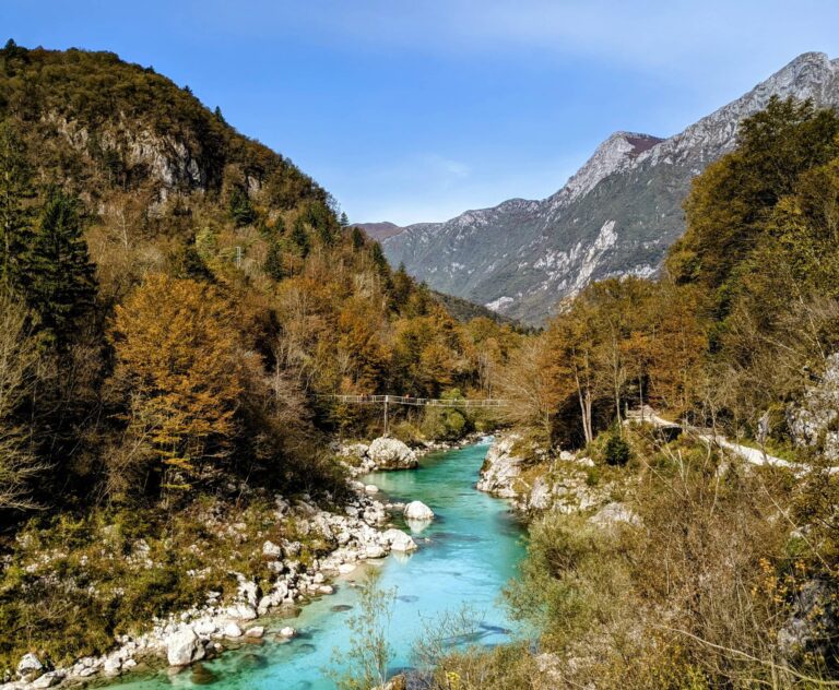 Autumn colours in Slovenia, forested hills with red, orange and yellow trees by a lake