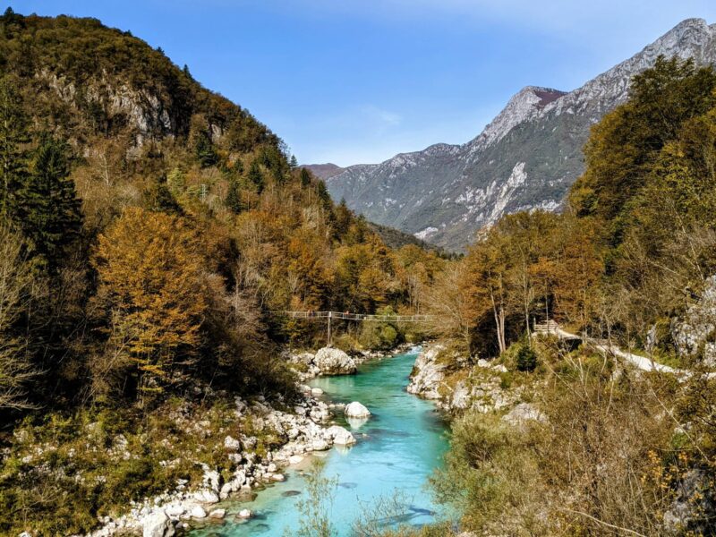 Autumn colours in Slovenia, forested hills with red, orange and yellow trees by a lake